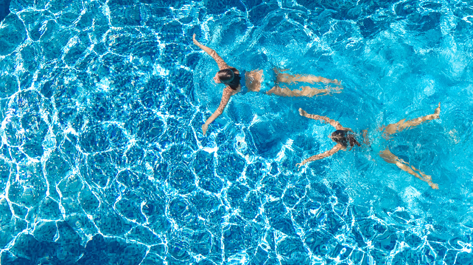 Aerial top view of girls in swimming pool on a french property