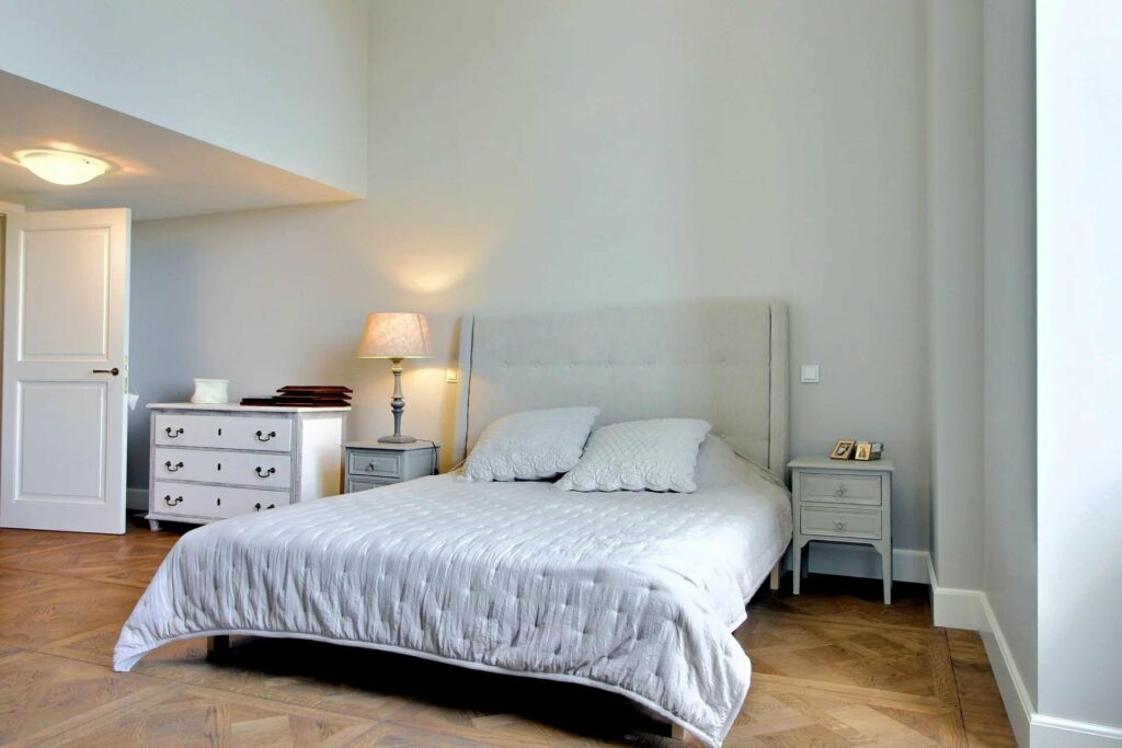 bedroom with large white bed and high ceilings