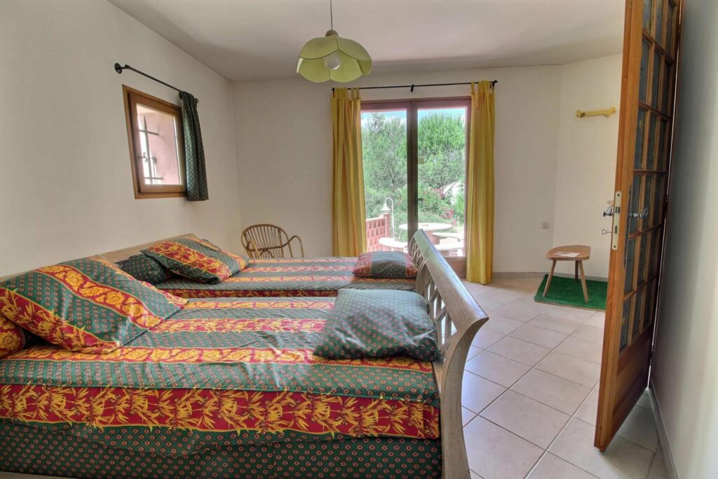 bedroom of house in south france with two double beds and sliding door to backyard pool