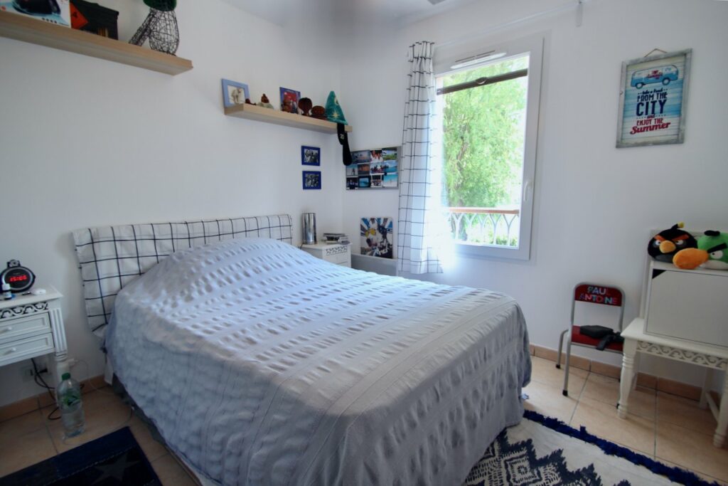 small bedroom with blue bedding and small window