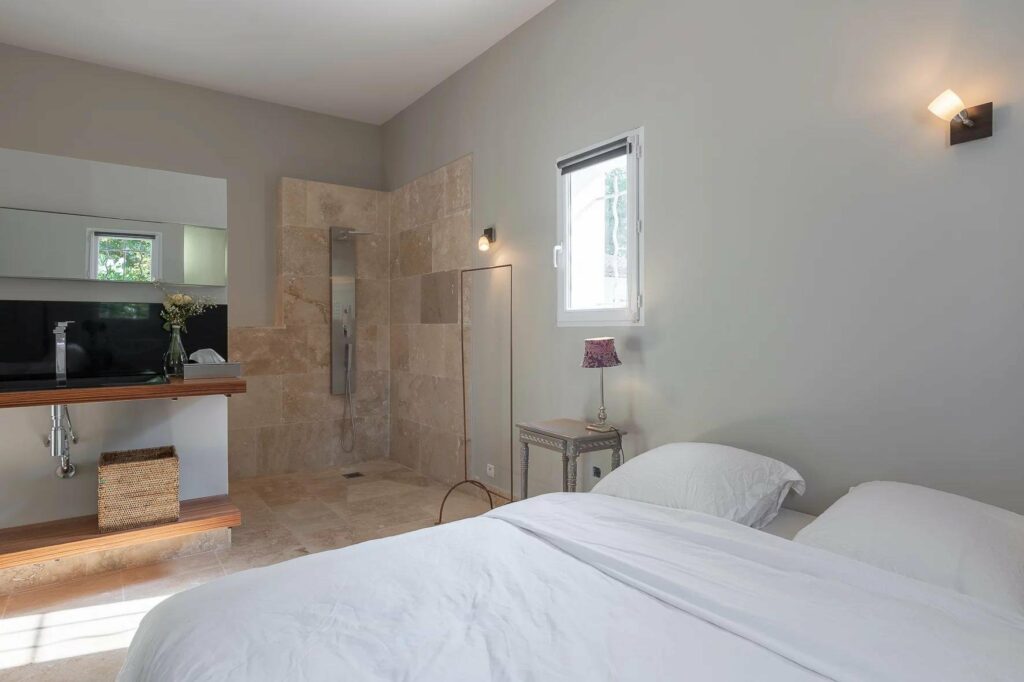 bedroom in draguignan villa with white walls and bed and small window next to bed