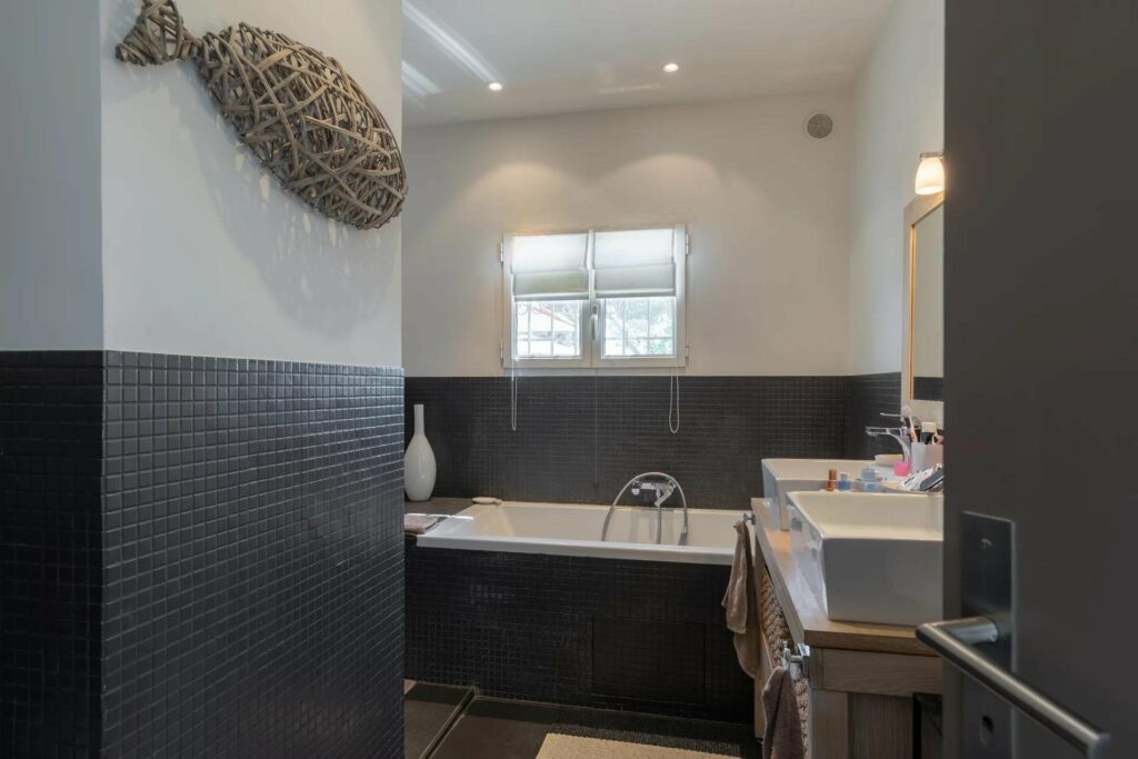 chic bathroom in biot villa with black tile walls and bathtub