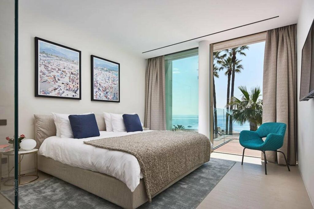 bedroom with beautiful sea view and white bedding with blue accent pillows