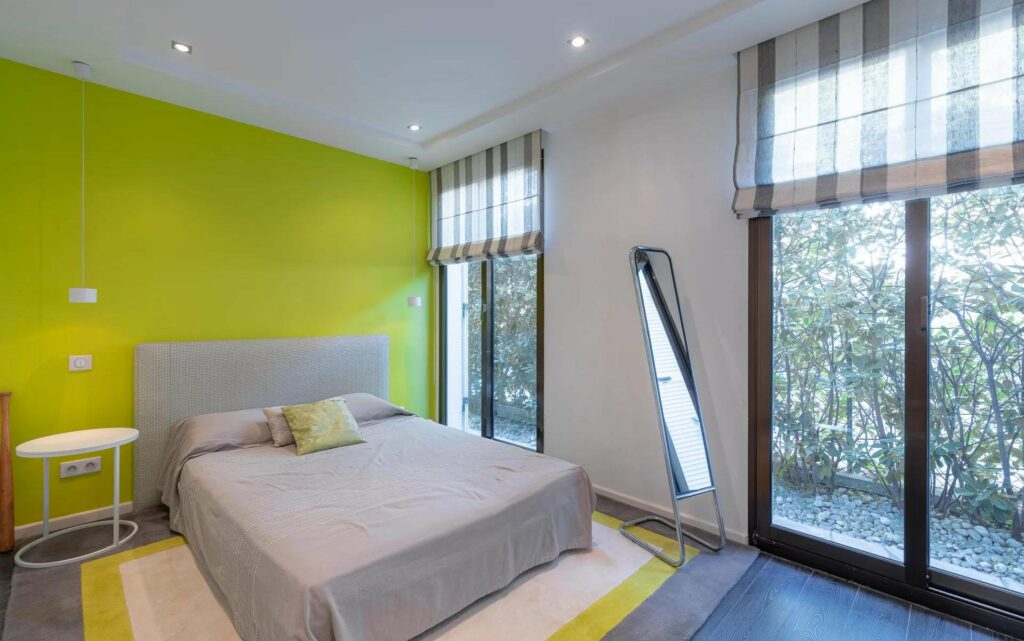green bedroom with grey bed and minimal design