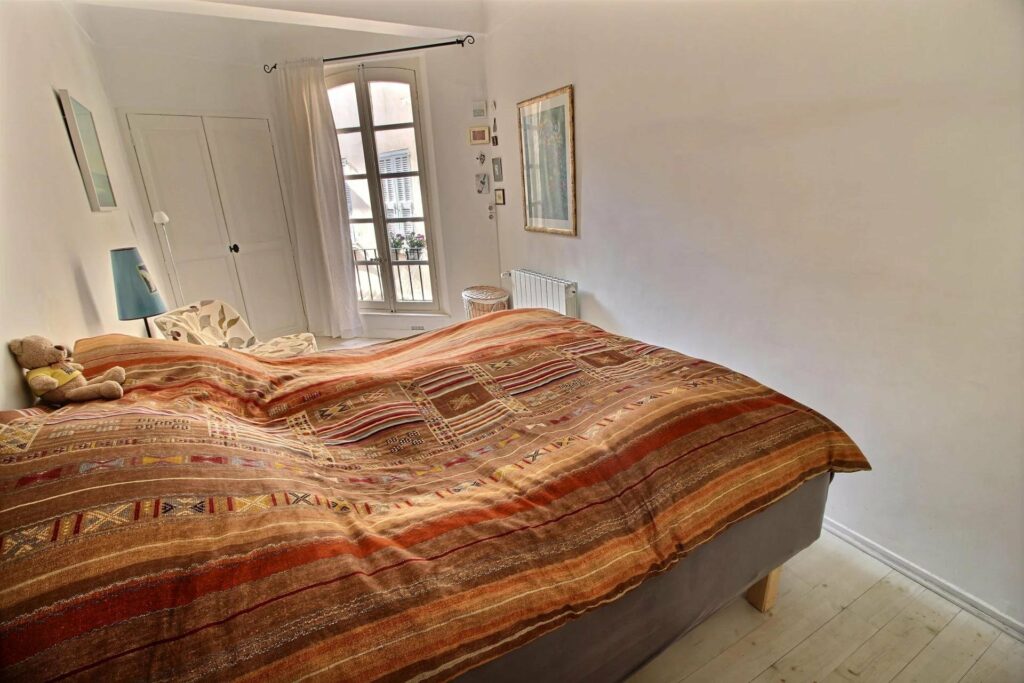 view of bed in room with dark orange bedding and open windows
