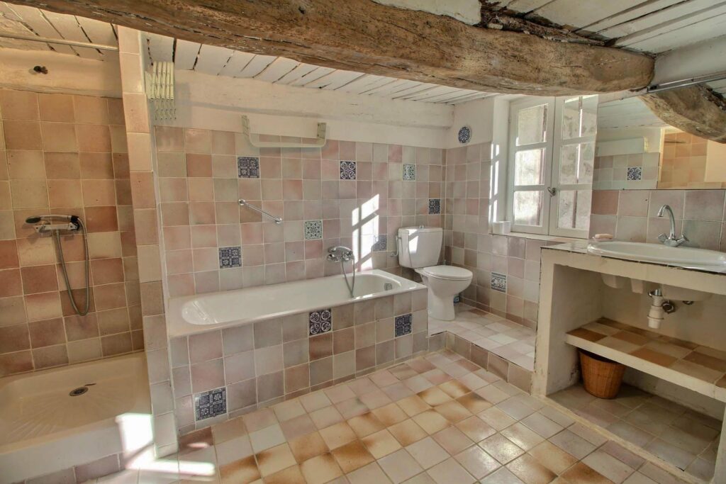 bathroom with stone tile floors and bathtub at seillans villa