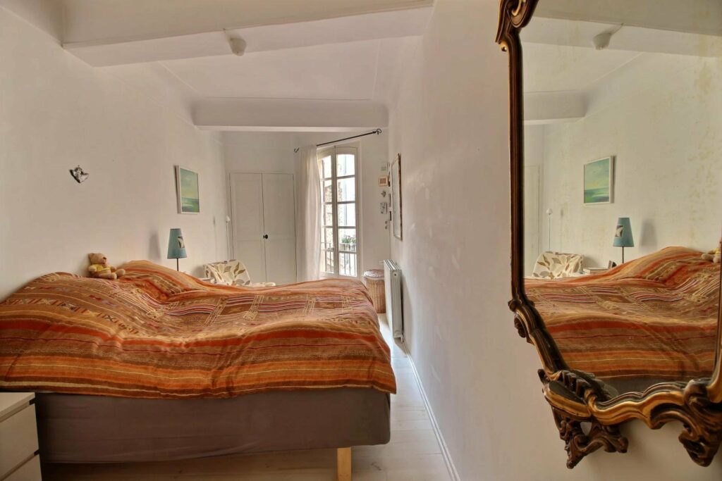 bedoom of apartment in antibes with dark orange bed and white walls