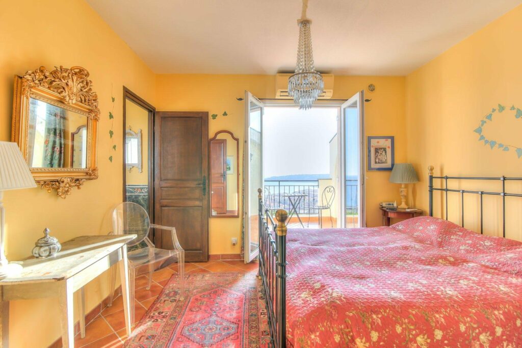 bedroom with red bedding and french doors with sea view in menton