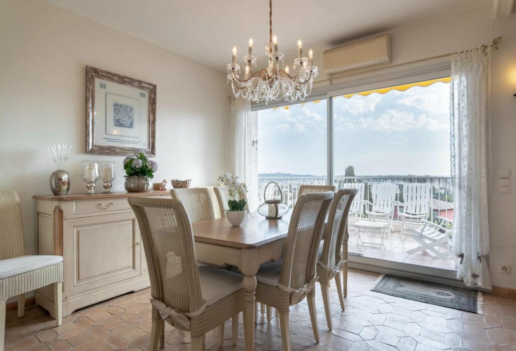 dining room with small table facing glass sliding door to terrace with view of antibes