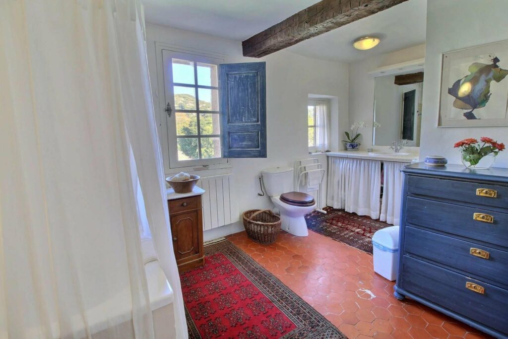 bathroom with red rug and rustic tile floors with high ceilings and exposed dark wood beams