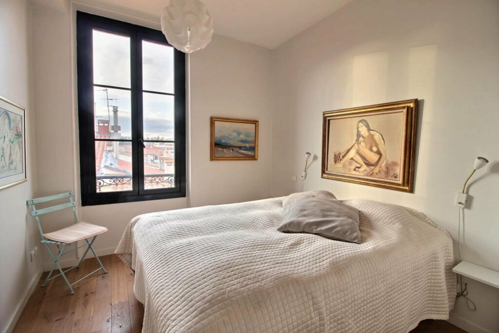 bedroom with white queen size bed and window with view of surrounding buildings