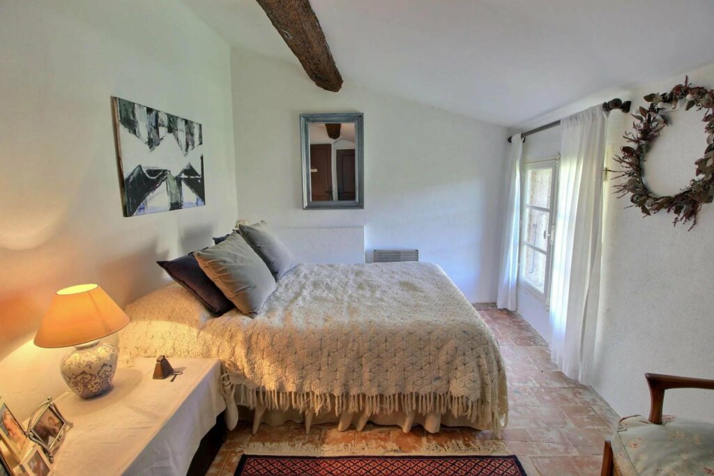 bedroom with large beige bed and exposed dark wood beams