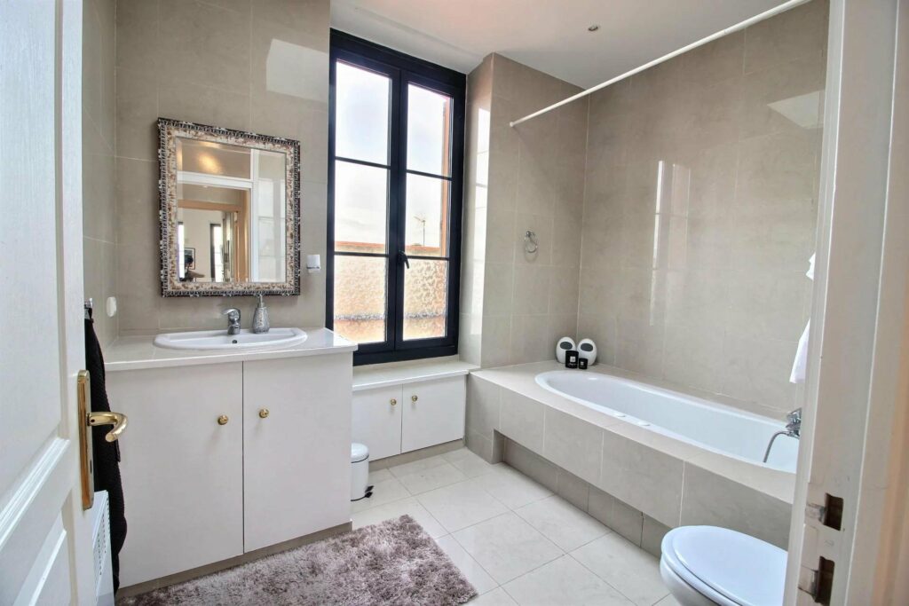 bathroom with white bathtub and large window