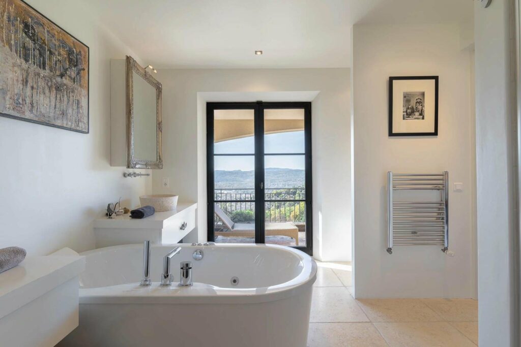 bathroom with large white bathtub facing french door with beautiful mountain view