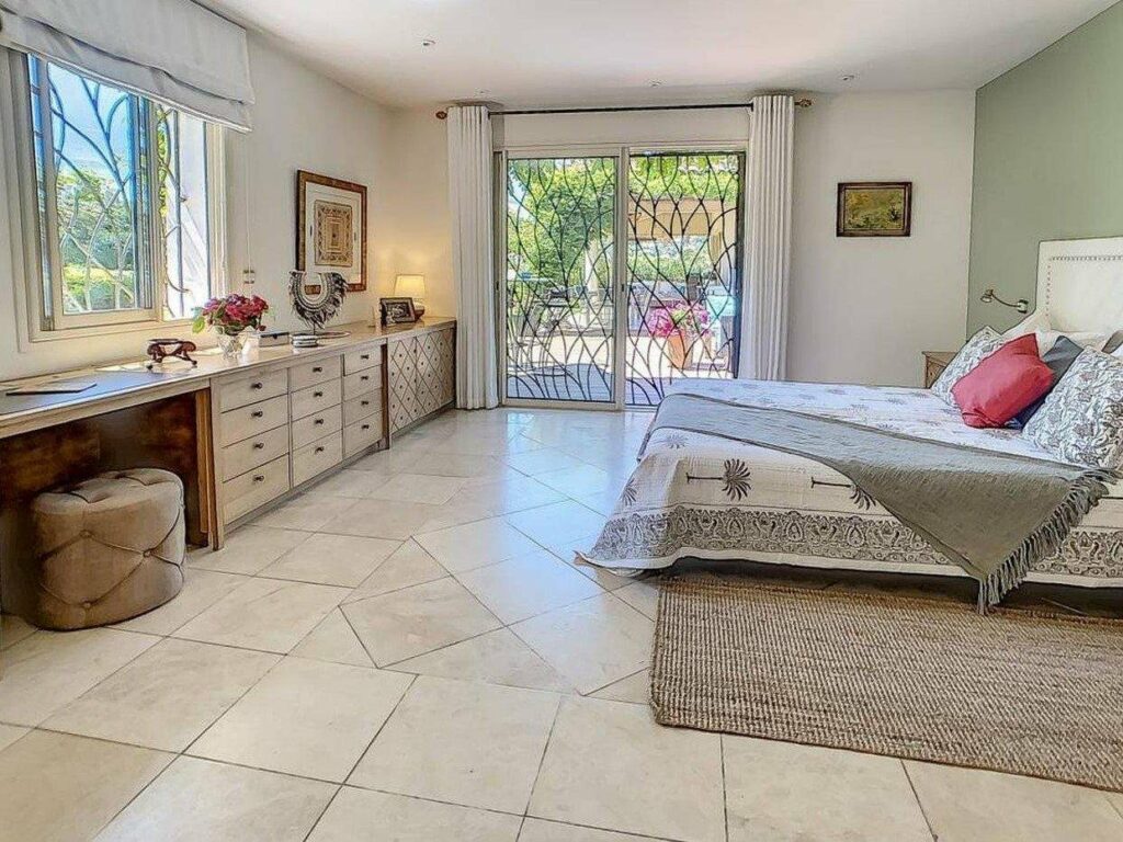 bedroom with beige tile floors and large king size bed with access to garden