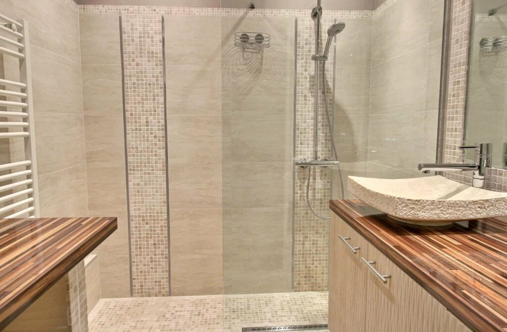 modern bathroom with light grey tile walls and large standing shower