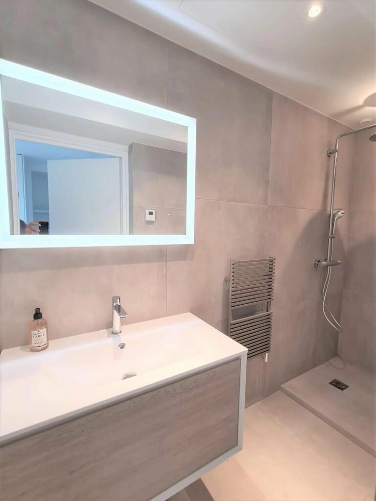 bathroom with large backlit mirror and standing shower