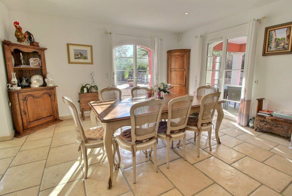 dining room with large wooden table and white tile floors and two sliding doors with access to backyard