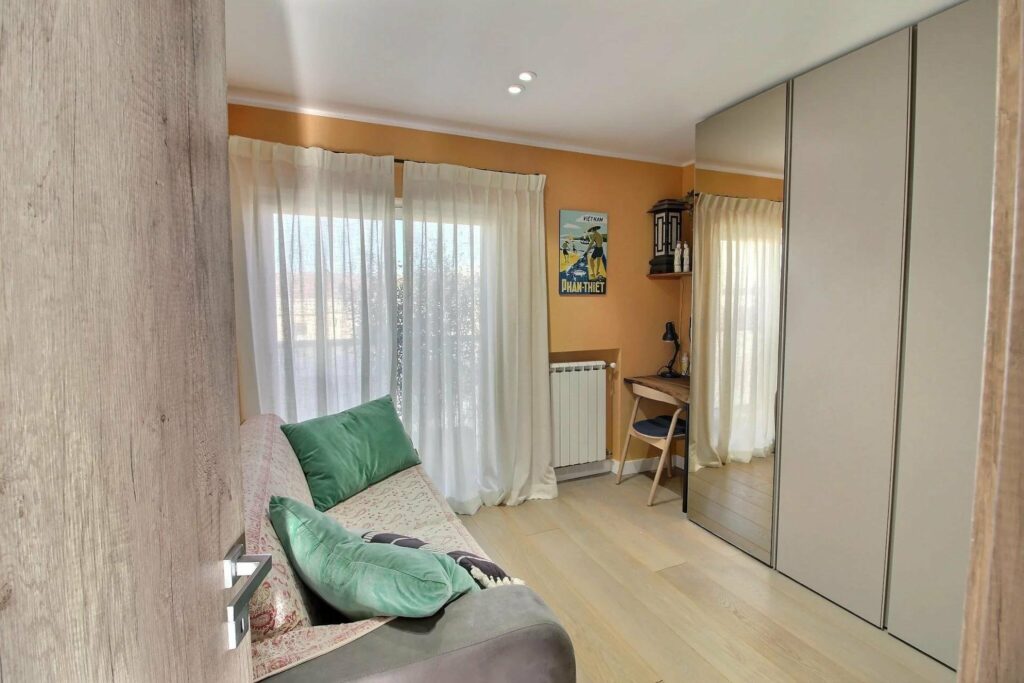 room with small grey couch and white tile floors and glass sliding door