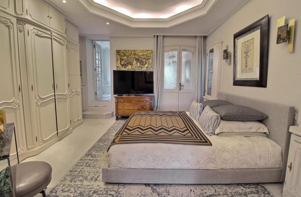bedroom with king size bed and grey design rug with flat screen TV in corner