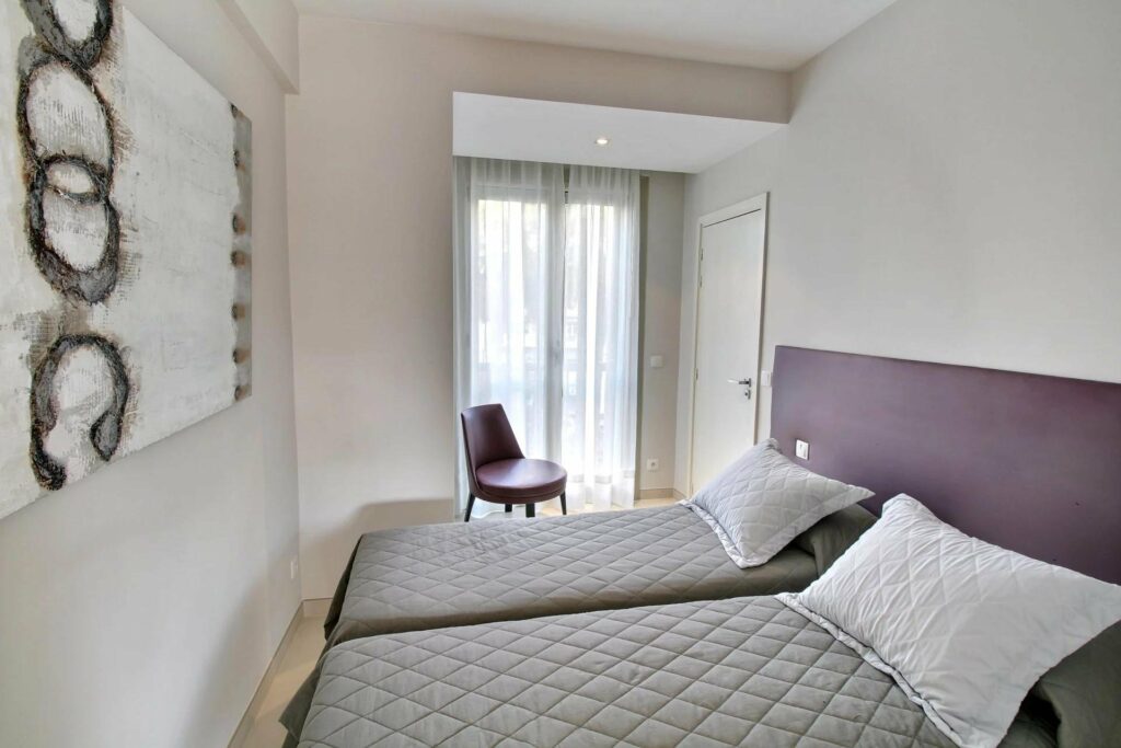 bedroom with two single beds next to purple chair in the corner of the room