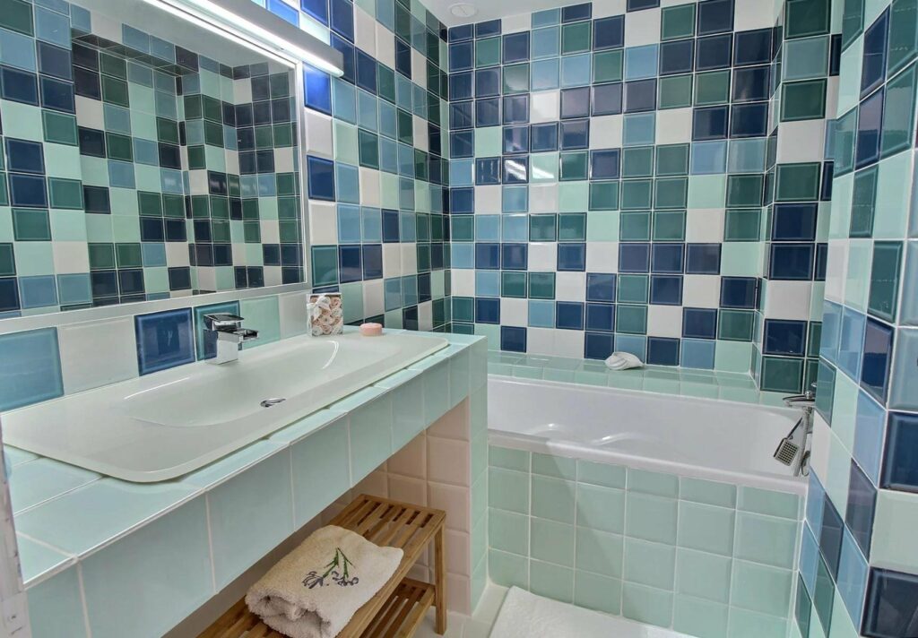 bathroom with blue and green tile walls and large bathtub