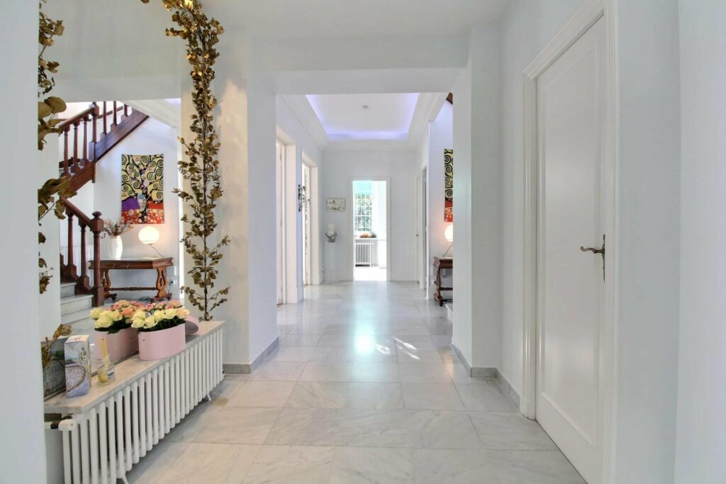 hallway with white walls and white tile floors leading to window to backyard