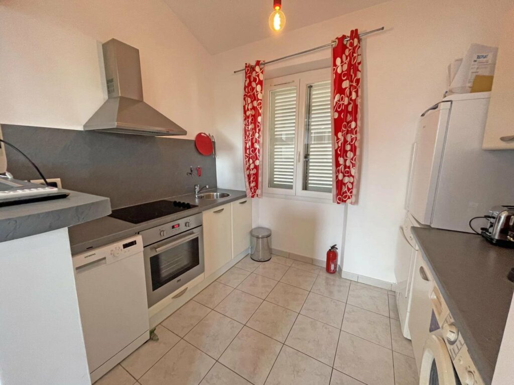 kitchen with beige tile floors and small window with red curtains