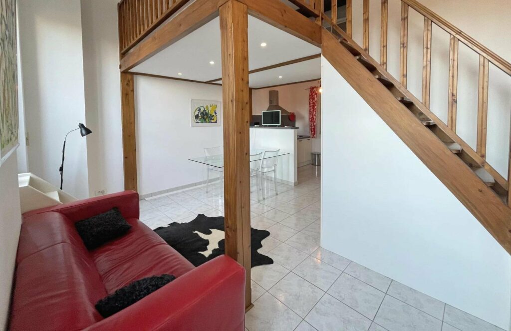 living room with red leather couch and wooden staircase leading upstairs
