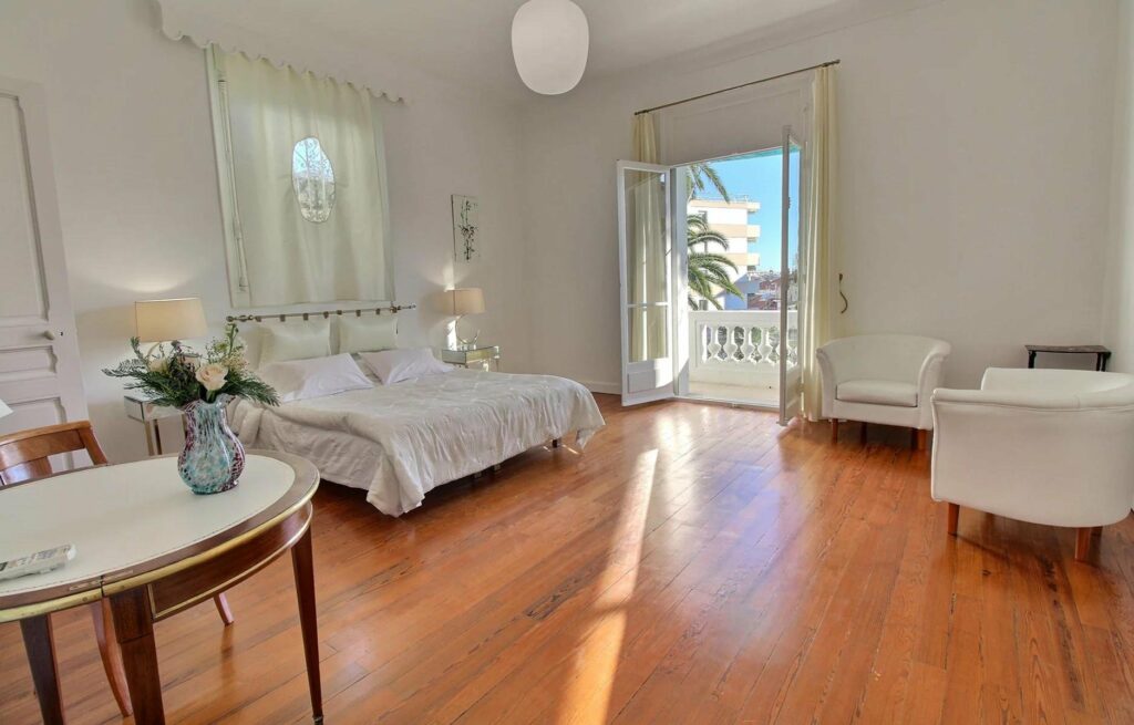 open bedroom of cannes townhouse with wooden floors and white queen size bed