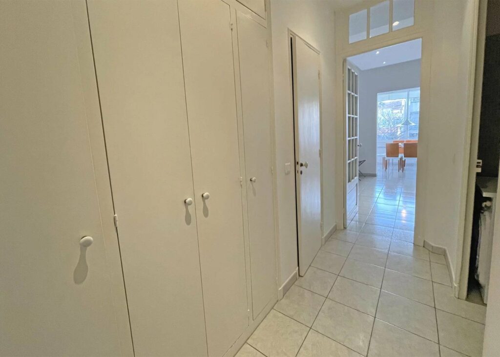 hallway with white closet and white tile floors