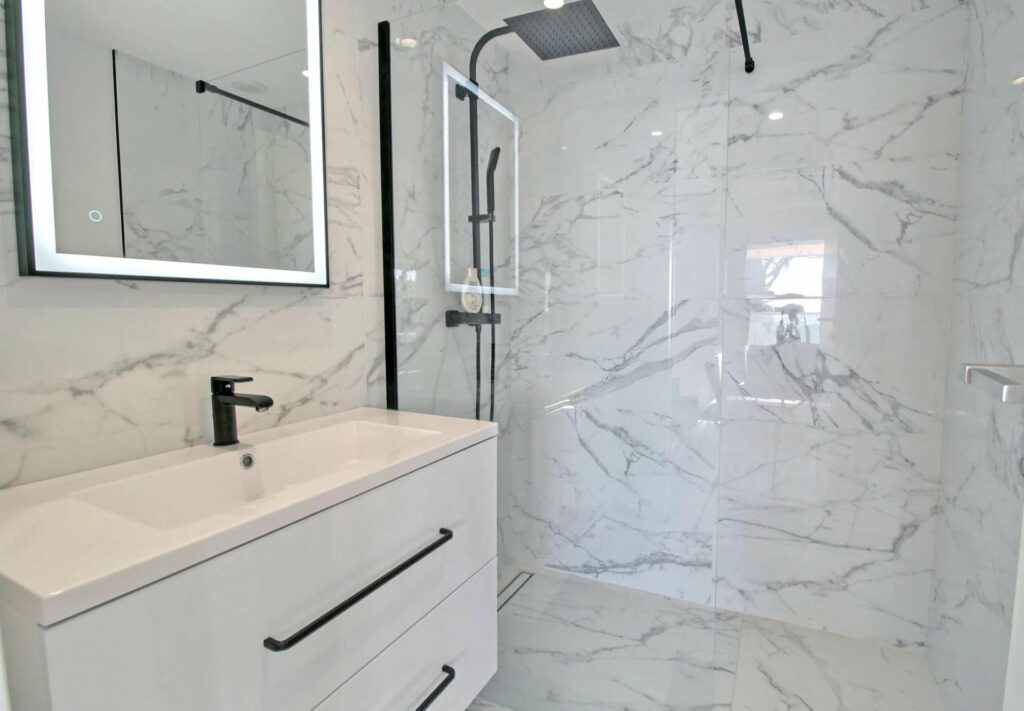 all white marble bathroom with standing glass shower
