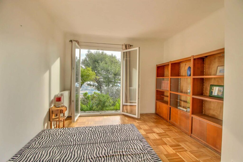 bedroom with warm wood floors and open french doors to terrace