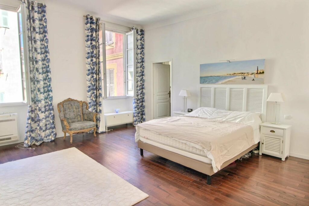 bedroom wih large white bed next to open window with view of streets old town nice