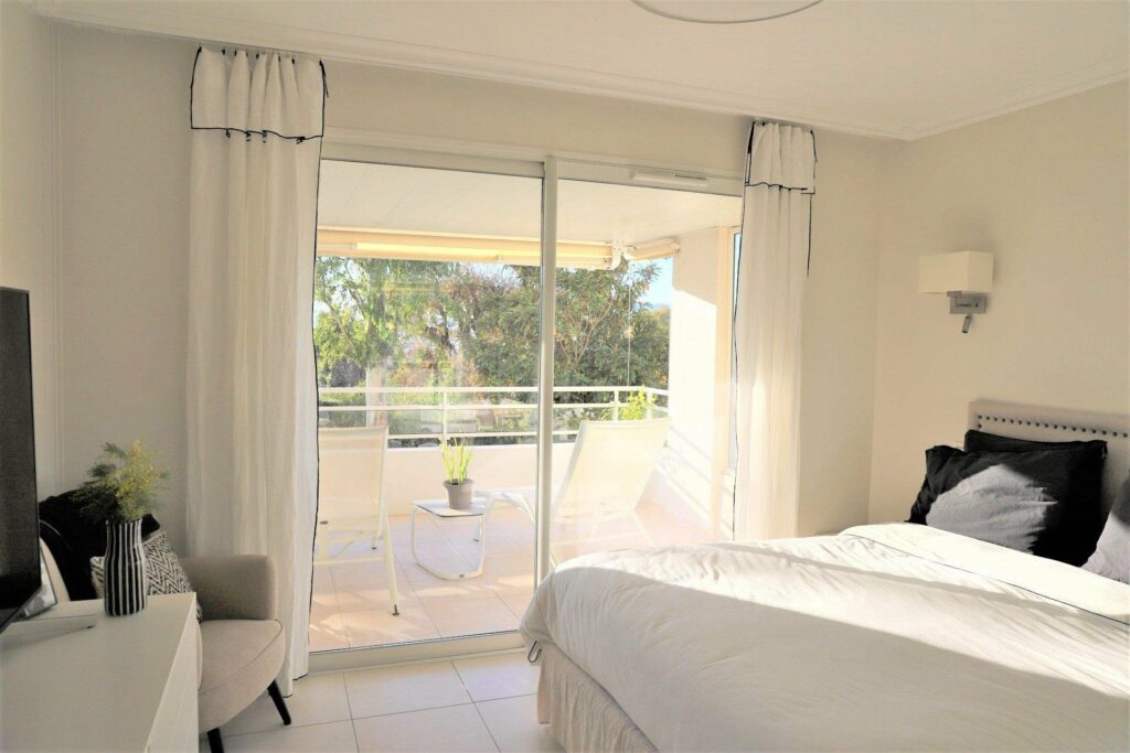 all white bedroom with large glass door access to terrace