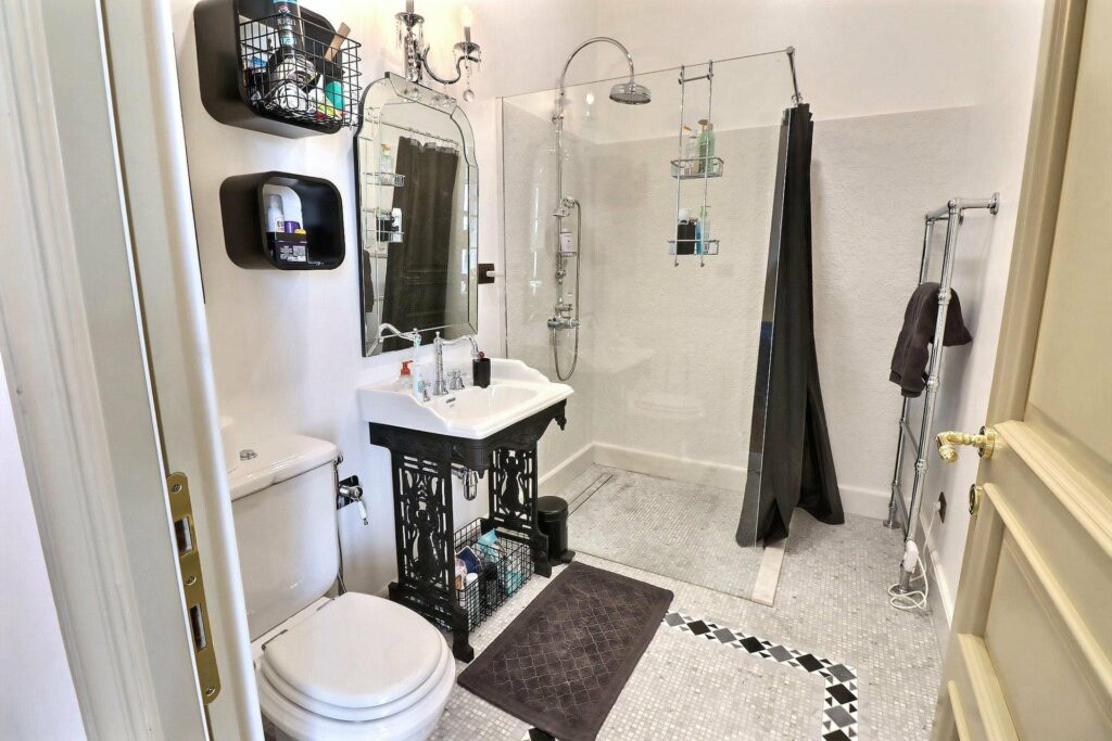 all white bathroom with black features and standing open shower