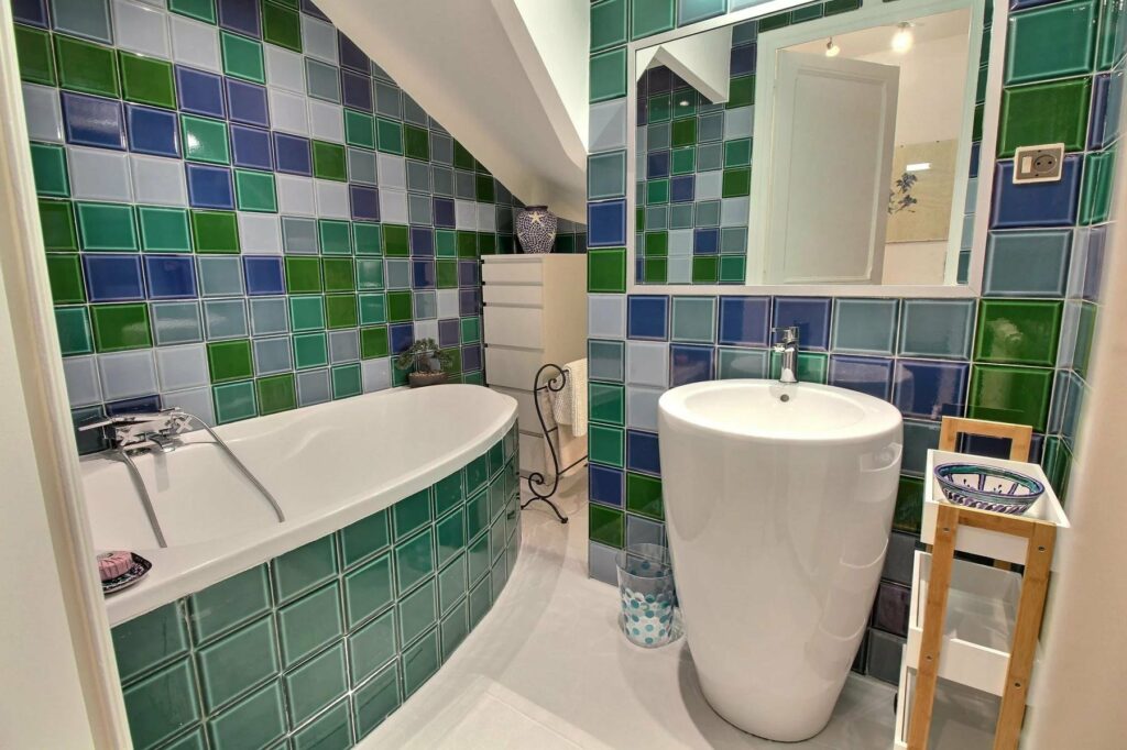 bathroom with blue and green tile floors with bathtub