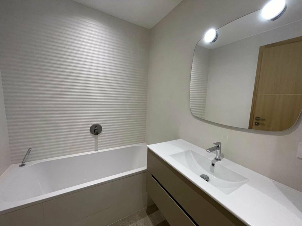 bathroom with white bathtub and small mirror above sink
