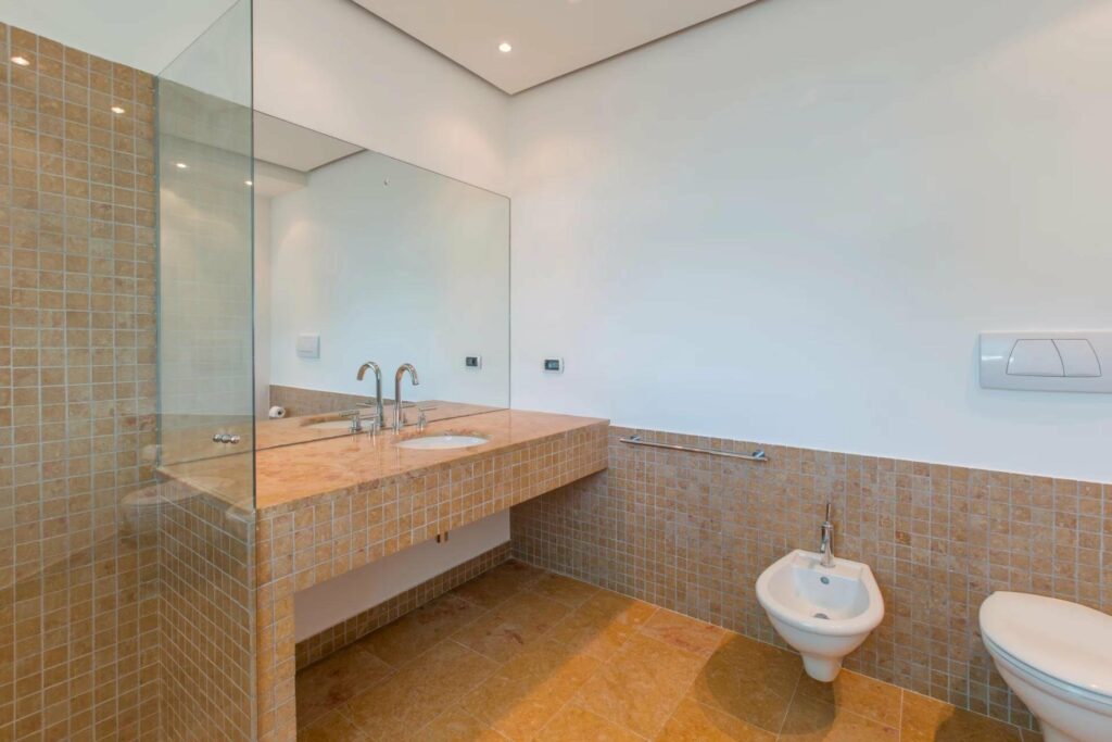 bathroom wit beige tiling and white walls with large rectangular mirror