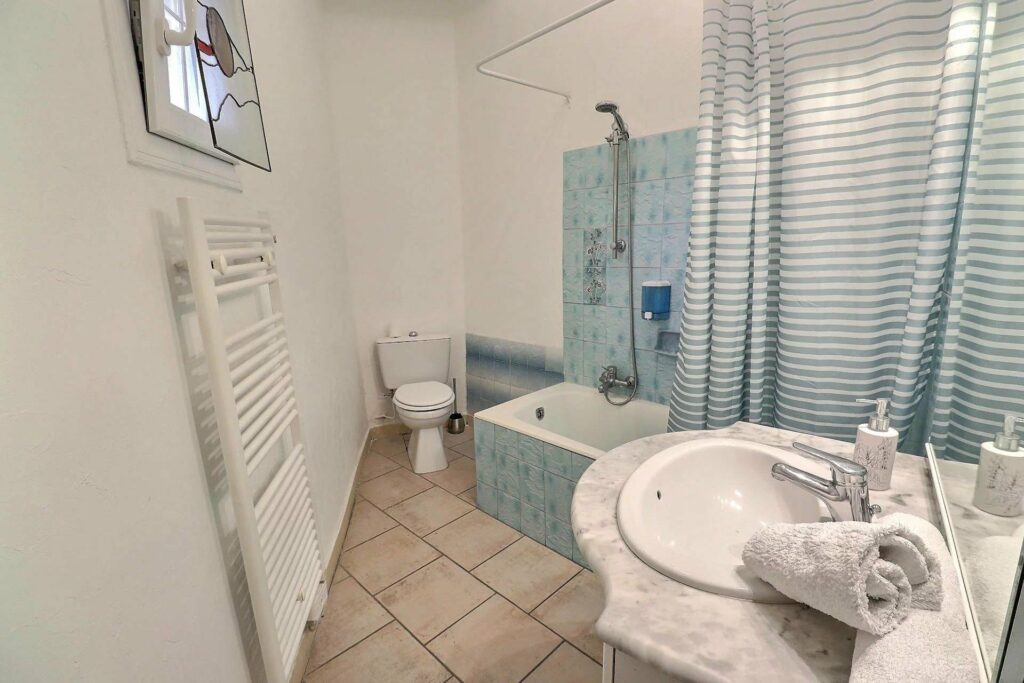 bathroom with beige tile floors and white walls and blue tiled bathroom