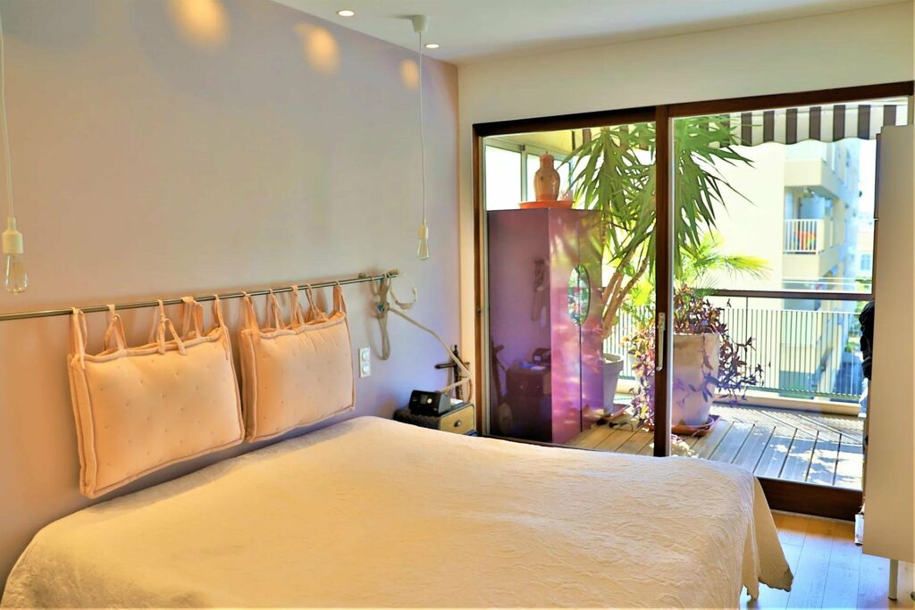 bedroom with queen size bed with white bedding next to terrace