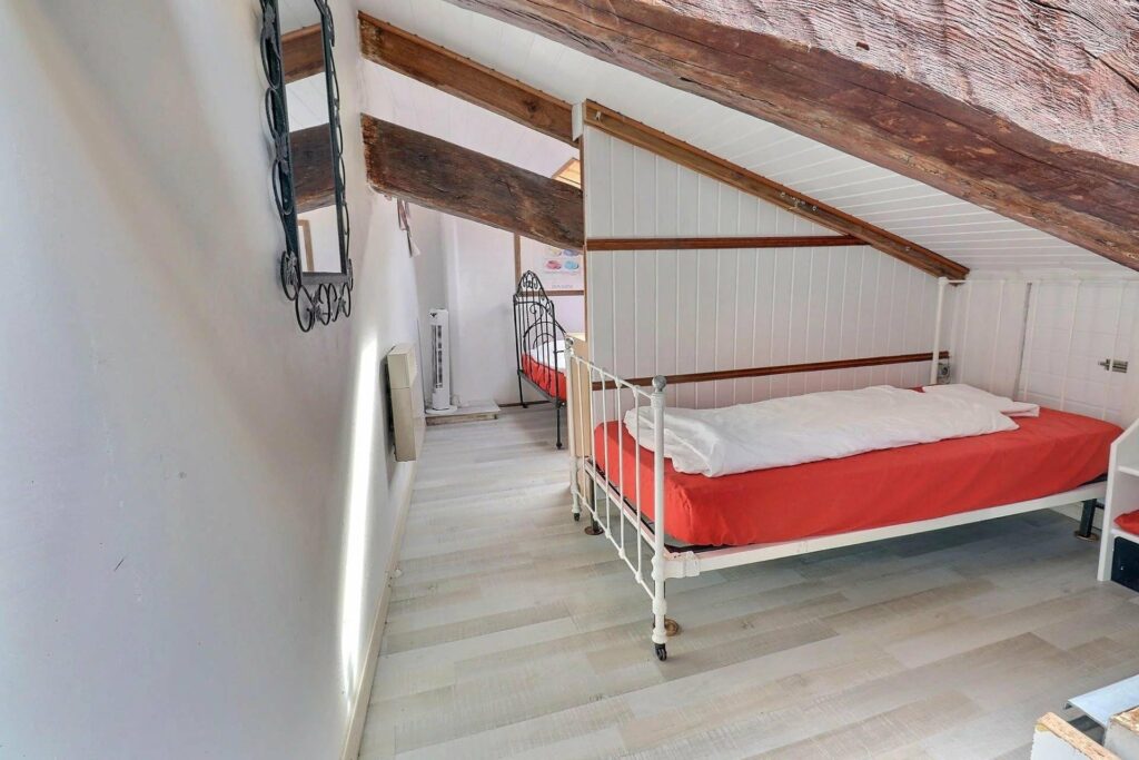 bedroom with two single beds with orange bedding and slanted ceiling