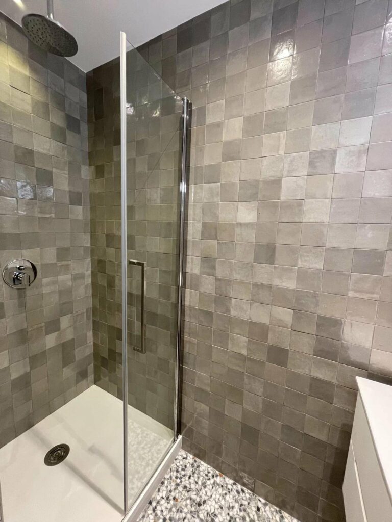 bathroom with grey square tiling on walls and standing glass shower