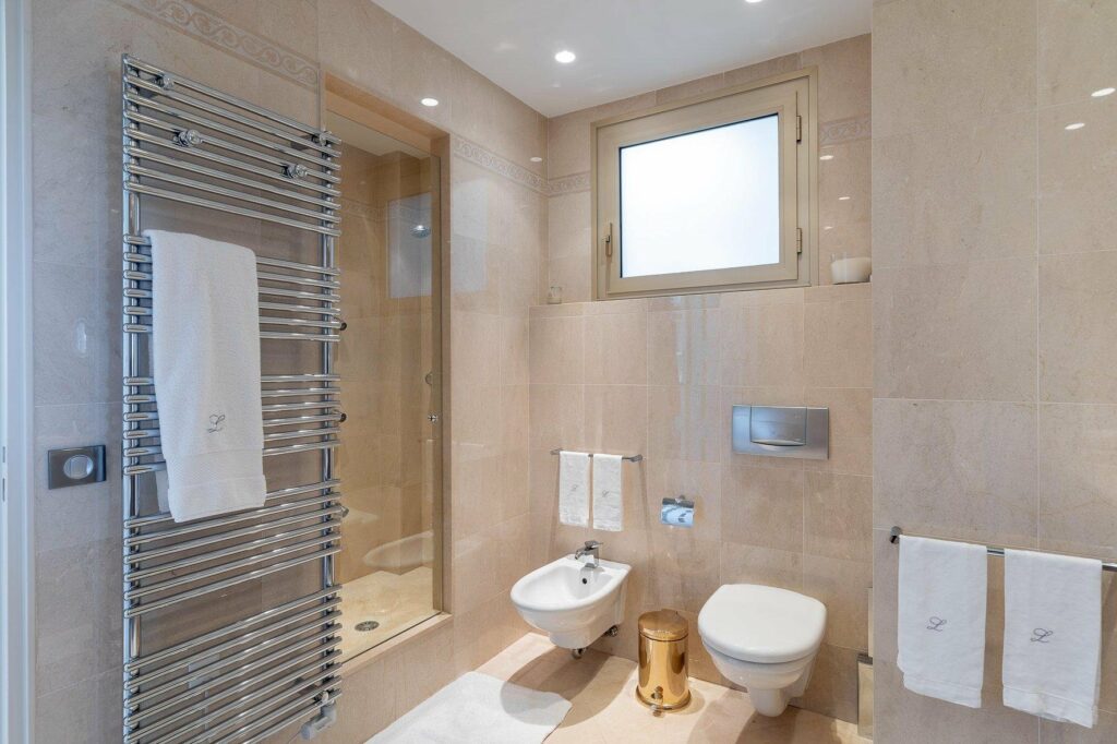 bathroom with beige tiling and small window above the toilet