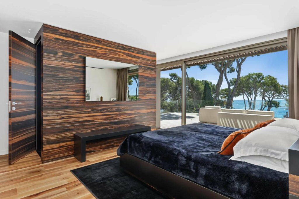 bedroom with wooden walls and floor to ceiling windows with access to pool