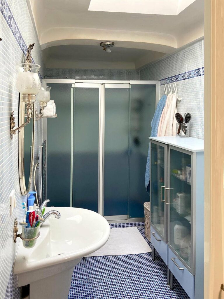 bathroom with glass sliding door and blue and white tiling