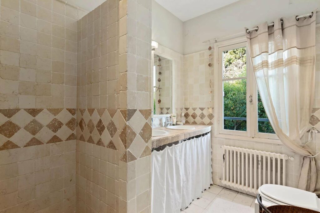 bathroom with beige interior and small window with view of garden