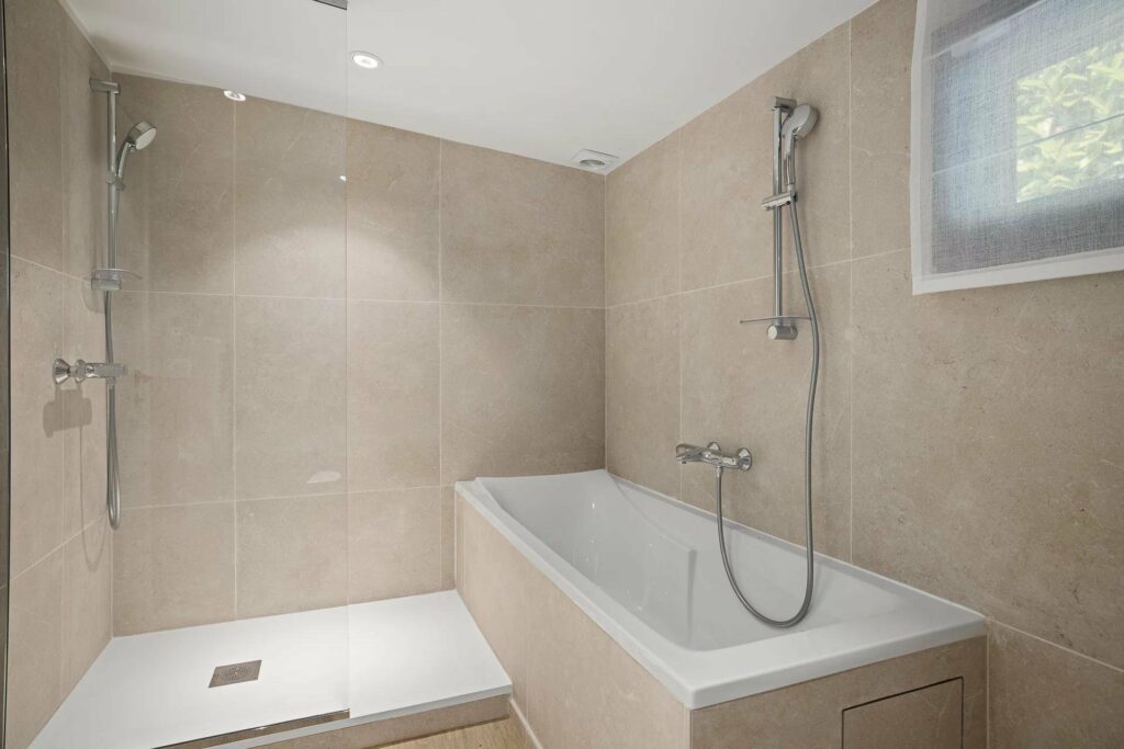 bathroom with white bathtub and beige tiling
