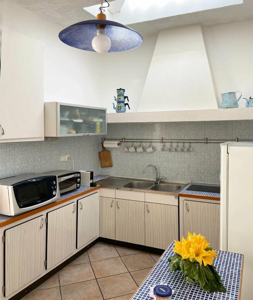 small kitchen with pale blue tiling and white cabinets