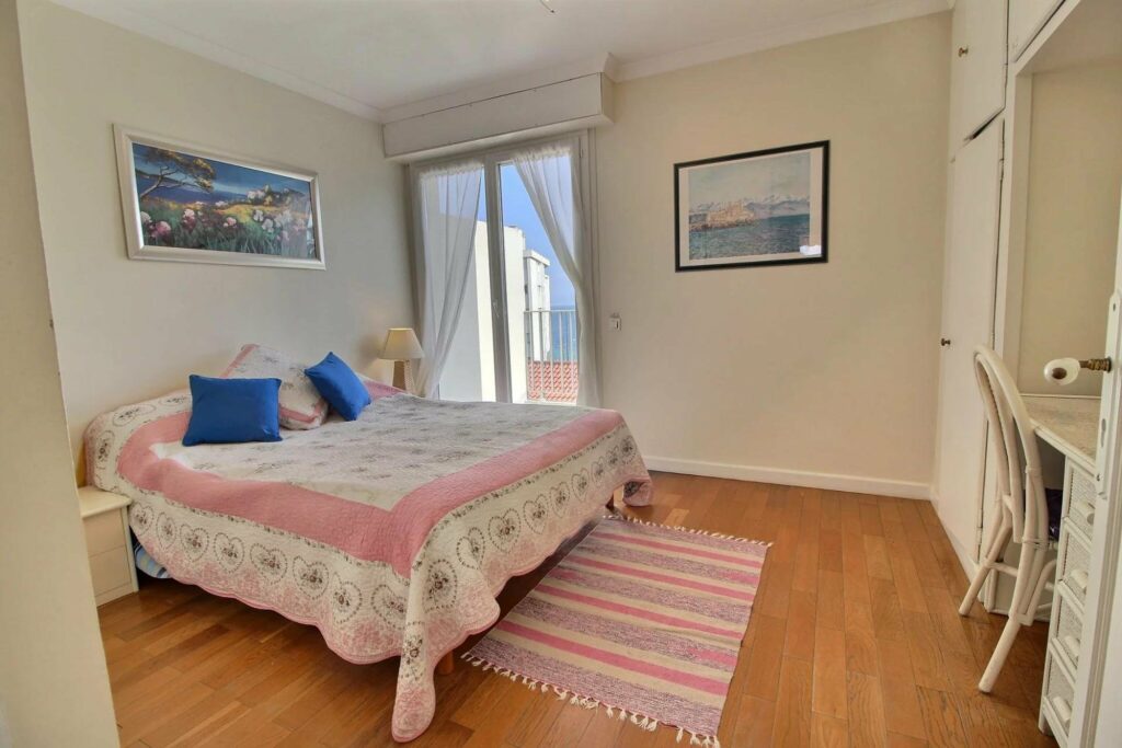bedroom with white and pink bedding with wooden floors